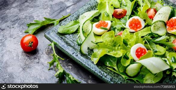 Spring vegetable salad with greens, cucumber, egg and red caviar. Salad with vegetables and greens