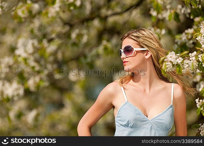 Spring - Young woman under blossom tree in orchard on sunny day