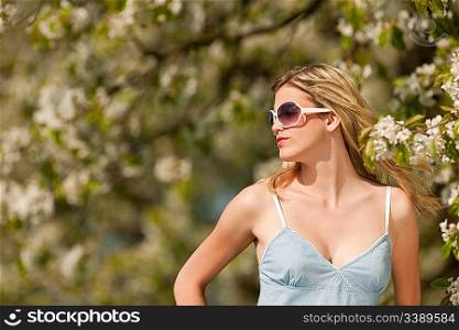 Spring - Young woman under blossom tree in orchard on sunny day