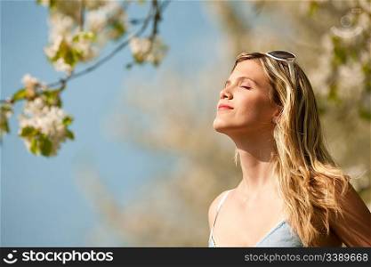 Spring - Young woman withs sunglasses under blossom tree enjoy sun