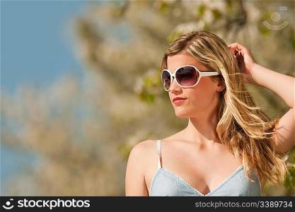 Spring - Young woman withs sunglasses under blossom tree enjoy sun