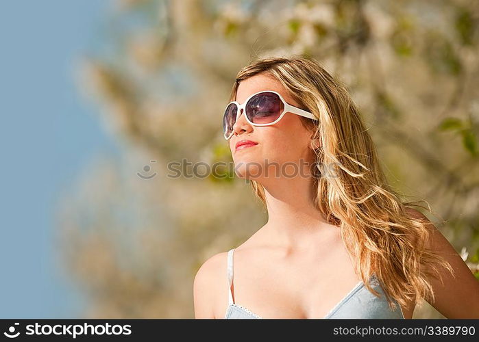 Spring - Young woman withs sunglasses under blossom tree enjoy sun