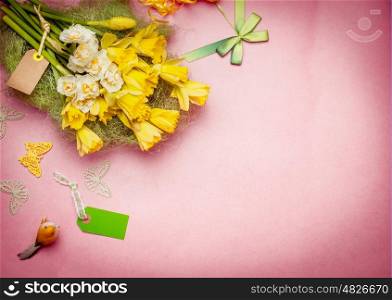 Springtime greeting flowers bunch with blank tag and decoration. Narcissus on pastel background, top view border