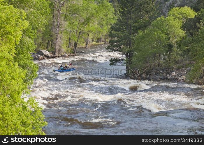 Springtime whitewater of Cache la Poudre River near Fort Collins, Colorado with a kayak in the middle of a rapid