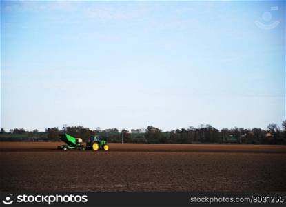 Springtime work with a tractor and machinery in a farmers field with black soil