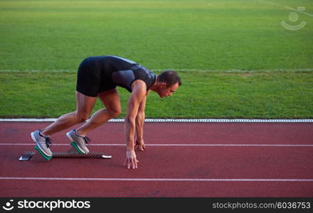 Sprinter leaving starting blocks on the running track. Explosive start.