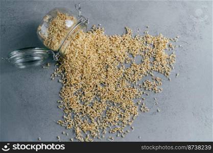 Sprouted buchwheat spilled from glass jar on grey background. Vegan organic sprouts. Eco products. Dieting and healthy nutrition concept