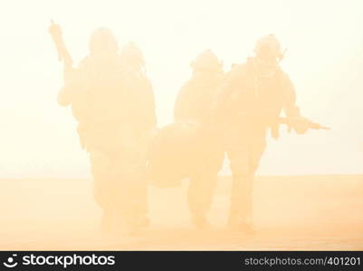 Squad of soldier evacuate the injured fellow in arms hiding in the smoke