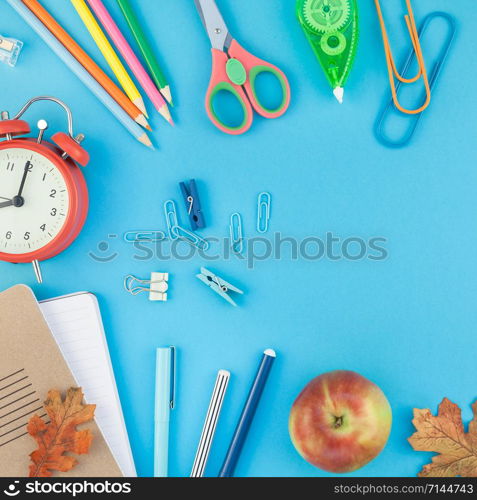 Square Creative flat lay top view back to school concept with alarm clock color school and office supplies on bright turquoise paper table frame background with copy space, template for text or design
