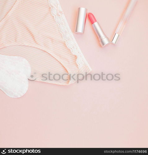 Square Feminine flat lay set of female panties and accessories, perfumes, lipstick and pads liners on pastel pink color background for fashion blog and social media with copy space for text
