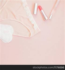 Square Feminine flat lay set of female panties and accessories, perfumes, lipstick and pads liners on pastel pink color background for fashion blog and social media with copy space for text