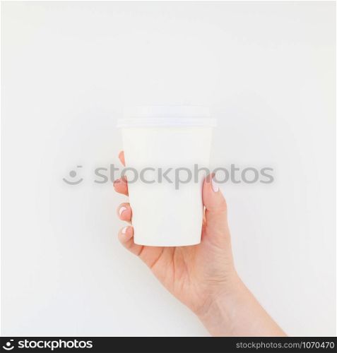 Square mock up image of woman hand holding paper coffee cup with copy space isolated on white background in minimalism style. Template for feminine blog, social media