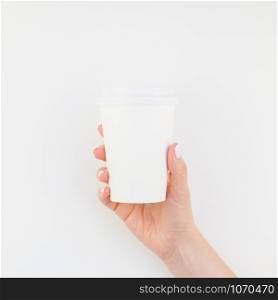 Square mock up image of woman hand holding paper coffee cup with copy space isolated on white background in minimalism style. Template for feminine blog, social media