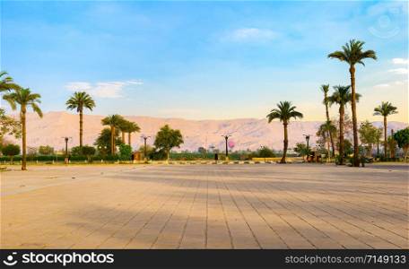 Square near Karnak Temple in Luxor with the view on palm trees and mountains at sunrise. Square near Karnak temple