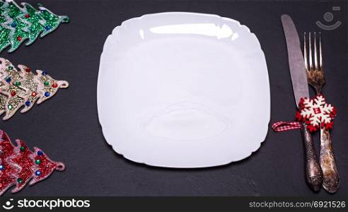 square white plate with iron vintage fork and knife and Christmas decorations