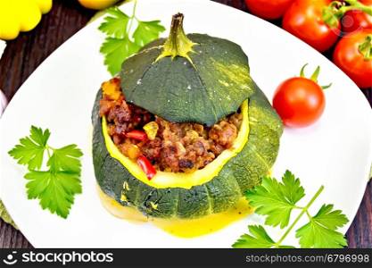 Squash green stuffed with meat, tomatoes and sweet pepper, garlic and parsley on a wooden board background