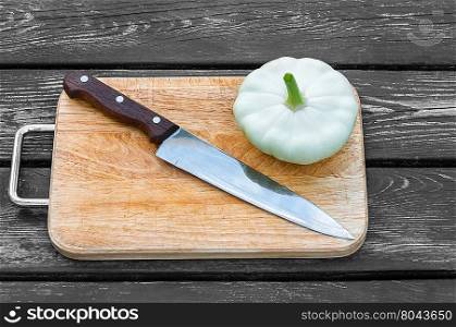 Squash on a cutting board on wooden background with a steel knife. Squash on a cutting board wooden background with steel knif