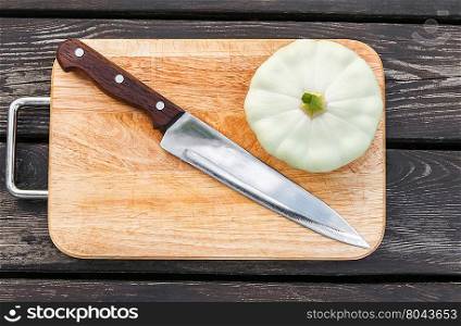 Squash on a cutting board on wooden background with a steel knife. Squash on a cutting board wooden background with steel knif