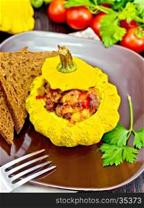 Squash yellow stuffed with meat, tomatoes and peppers, bread in a brown plate, tomatoes, parsley and fork on the background of wooden boards
