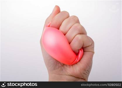 Squeezing pink balloon with hand on a white background