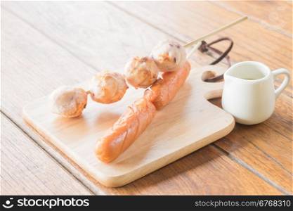 Squid ball and hotdog grilled on wooden plate, stock photo