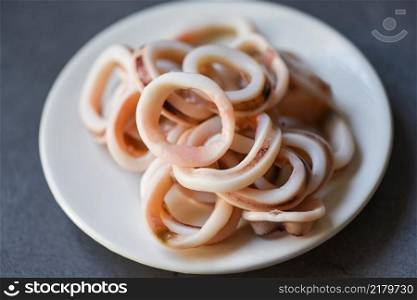 squid rings on white plate, Fresh squid cooked boi≤d with≤ttuce ve≥tab≤salad on dark background