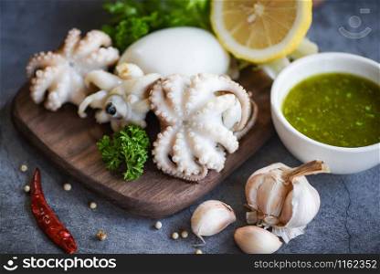 Squid salad spices lemon garlic chili sauce on wooden cutting board background / cooked food squids octopus or cuttlefish at seafood restaurant