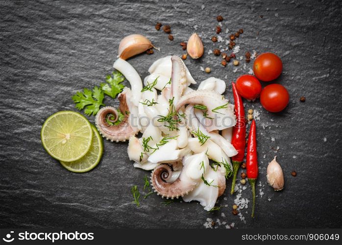 squid salad with lemon herbs and spices on dark background top view / Tentacles octopus cooked appetizer food hot and spicy chilli sauce seafood cooked served on black plate in the restaurant