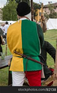 Squire with Black Hat, Two-coloured Shirt and Dagger in his Belt during Medieval Event Reconstruction
