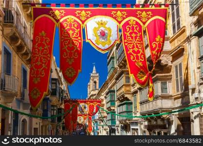 St Augustine Feast of Valletta, Malta. Festively decorated street with banners for St Augustine Feast in the old town of Valletta, Malta. Flaming, arrow pierced heart - symbol of St Augustine