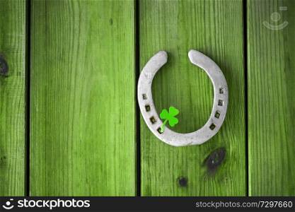 st patrick&rsquo;s day concept - horseshoe with shamrock on green wood boards. horseshoe with shamrock on green wood boards