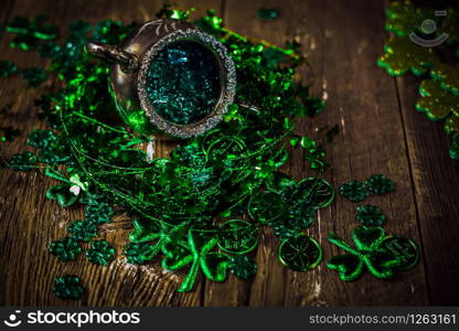 St.Patrick&rsquo;s day holiday symbol. Shamrocks and antique silver potty with coins on an old rustic wood background. Close up view. Selective focus. Bokeh.