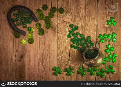 St. Patricks Day composition. Shamrocks, horseshoe, coins and silver pot on vintage style wood background. St.Patrick&rsquo;s day holiday symbol. Top view, copy space.