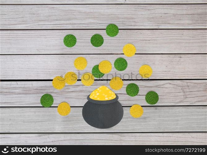 st patricks day, holidays and celebration concept - pot of gold and coins made of paper on grey wooden boards background. pot of gold and coins for st patricks day