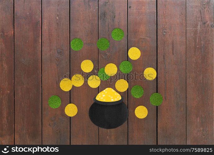st patricks day, holidays and celebration concept - pot of gold and coins made of paper on wooden background. pot of gold and coins for st patricks day on wood