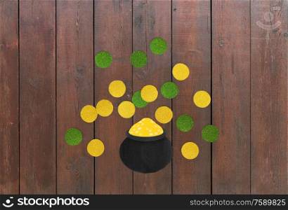 st patricks day, holidays and celebration concept - pot of gold and coins made of paper on wooden background. pot of gold and coins for st patricks day on wood