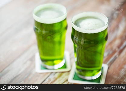 st patricks day, holidays and celebration concept - two glasses of green beer on wooden table. two glasses of green beer on wooden table