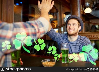 st patricks day, people, leisure and gesture concept - happy male friends drinking green beer and making high five at bar or pub. friends with green beer making high five at pub