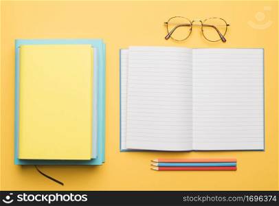 stack books opening blank copybook with arranged pencils