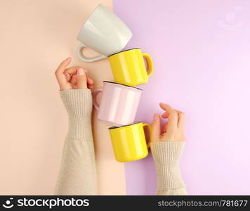 stack ceramic cups are supported by a female hand on a beige lilac background, copy space