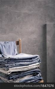 Stack denim jeans at chair. Stack of jeans near abstract background texture surface