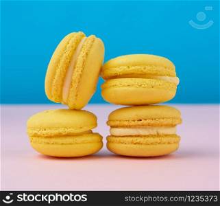 stack of baked round yellow lemon macarons on a blue-pink background, delicious and delicious French dessert