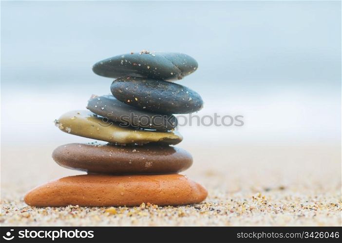Stack of beach stones on sand. Ocean in the background