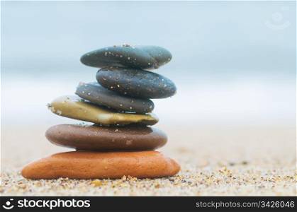 Stack of beach stones on sand. Ocean in the background