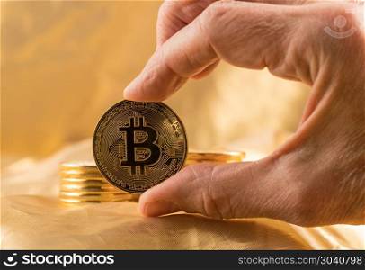 Stack of bitcoins with gold background. Stack of bit coins or bitcoin held in man&rsquo;s hand on gold background to illustrate blockchain and cyber currency. Stack of bitcoins with gold background