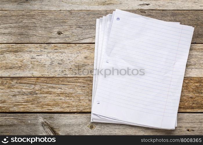 stack of blank notebook pages on a rustic, weathered wood background