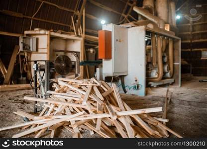 Stack of boards near woodworking machine in sawdust, nobody, lumber industry, carpentry. Wood processing on factory, forest sawing in lumberyard, sawmill. Stack of boards near woodworking machine, sawmill