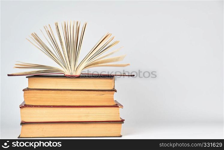stack of books and an open book with yellow pages on a white background, copy space