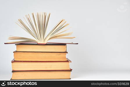 stack of books and an open book with yellow pages on a white background, copy space