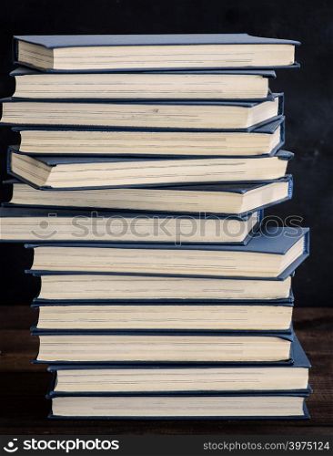 stack of books in a blue cover on a brown wooden table, close up